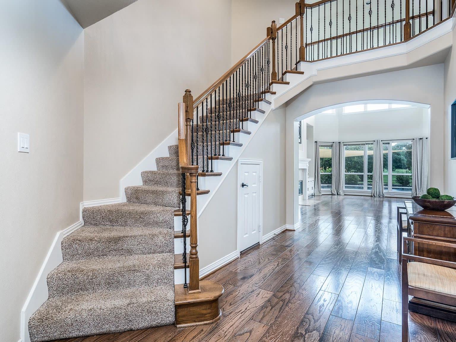 Formal living room with a limestone fireplace, wood floors, and a wall of windows to the backyard